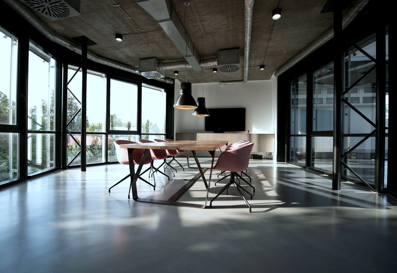 Office meeting room with a polished floor, long table and large windows